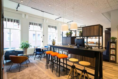 海牙ibis Styles Den Haag City Centre的一个带橙色椅子的厨房和一个位于客房内的酒吧