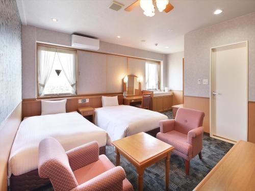 菊池市Green Rich Hotel Aso Kumamoto Airport (Artificial hot spring Futamata Yunohana)的酒店客房带两张床和一张桌子以及椅子。