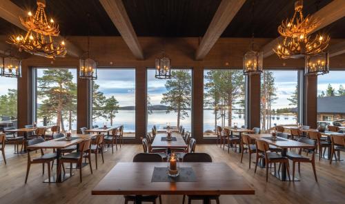 伊纳利Wilderness Hotel Inari & Igloos的餐厅设有桌椅和大窗户。