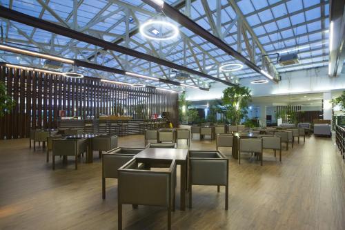 克孜拉阿奇华辛顿度假酒店及水疗中心的餐厅设有桌椅和玻璃天花板