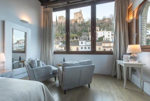 格拉纳达阿尔拜辛光芒酒店的一间卧室配有一张床和两把椅子,并设有一个大窗户