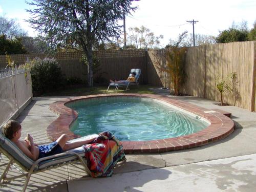 谢珀顿乡村之家汽车旅馆的两人躺在小泳池旁的椅子上