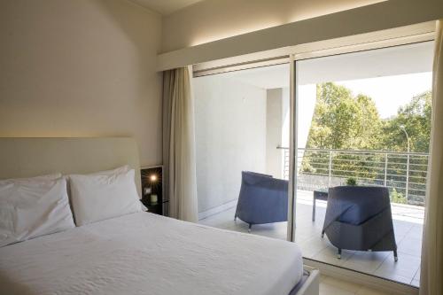 罗马朗格塔维尔套房酒店的一间卧室配有一张床和两把椅子,并设有一个阳台