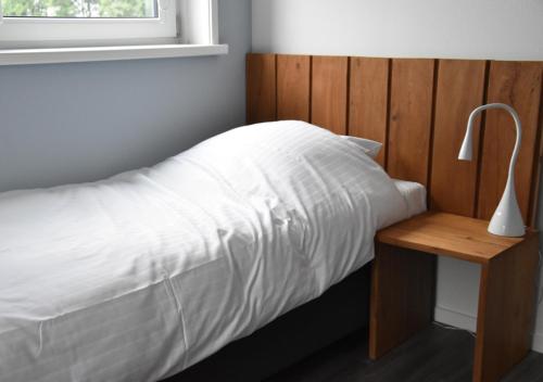 BirdaardWaterdorp Burdaard的一张铺有白色床单的床和木制床头板