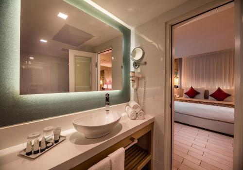 埃拉特埃斯特拉马里斯酒店的一间带水槽和镜子的浴室以及一张床