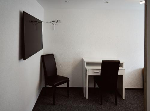 上科亨Boardinghouse Apart-Hotel的墙上的房间里设有两把椅子和一张桌子