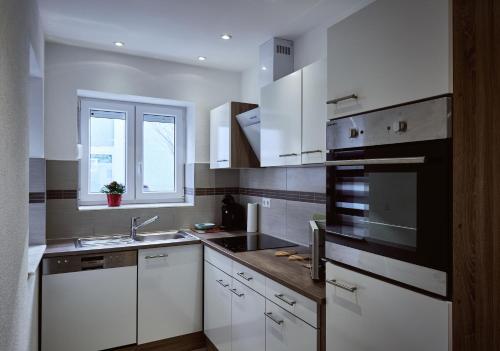 上科亨Boardinghouse Apart-Hotel的厨房配有白色橱柜、水槽和窗户。