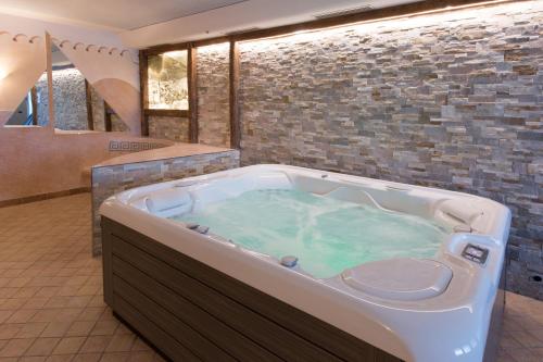 纳兹-夏韦斯Hotel Föhrenhof的一间带石墙的浴室内的热水浴缸