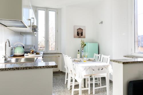 科莫Lora Como Apartment的白色的厨房配有白色的桌子和椅子