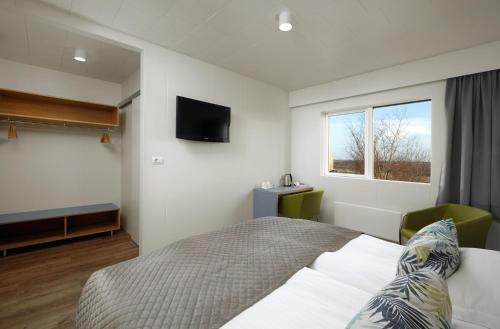 教堂城Hotel Klaustur的卧室配有一张床,墙上配有电视。