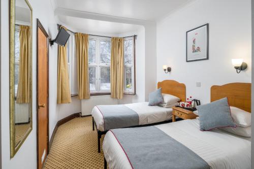 伦敦OYO Abbey Hotel, London Shepherd's Bush Market的酒店客房,设有两张床和镜子