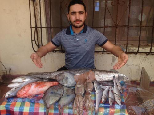 Villa BensHotel El ghazi的站在一大堆鱼旁的人