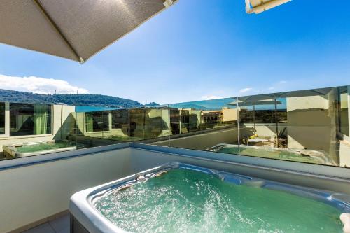罗希姆诺Atrium Ambiance Hotel的阳台上的按摩浴缸,配有绿水