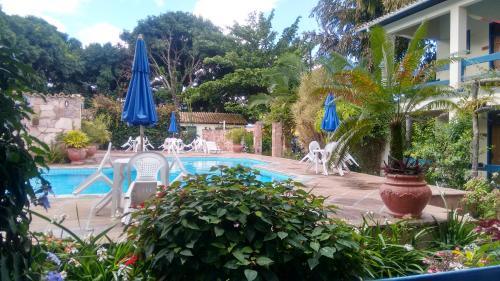 穆库热Pousada Mucugê的房屋旁的游泳池配有椅子和遮阳伞