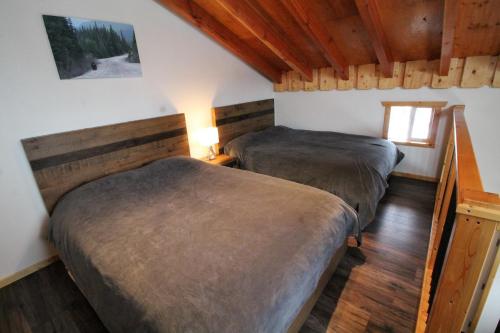 Anahim LakeRed Cariboo Apartments的铺有木地板的客房内的两张床