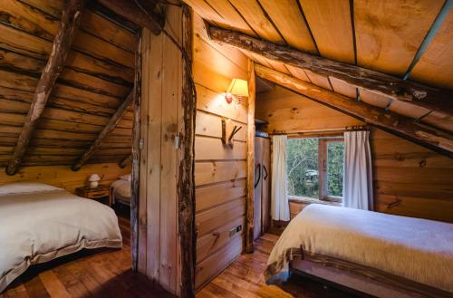 惠洛惠洛回罗回罗山林小屋的小木屋内一间卧室,配有两张床