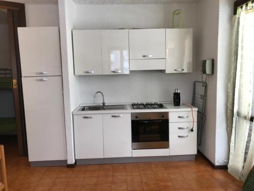 皮亚扎托雷Il Capriolo的厨房配有白色橱柜、水槽和炉灶。