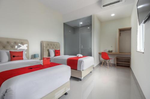 北干巴鲁RedDoorz near Mall SKA Pekanbaru的酒店客房配有两张床和一张书桌