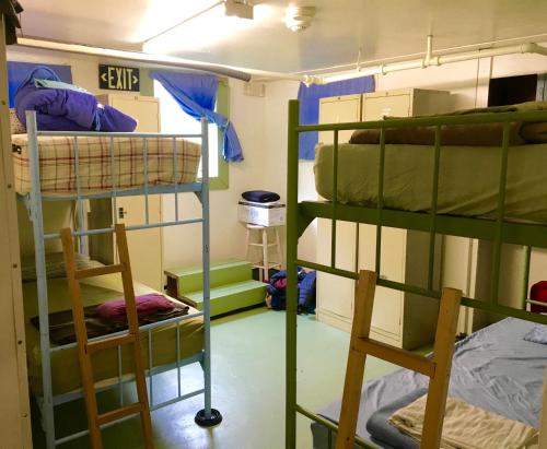 安克雷奇Base Camp Anchorage Hostel的带三张双层床和两把椅子的房间