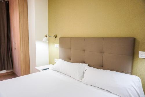 毕尔巴鄂Hotel Lidar的卧室配有一张带白色床单和枕头的大床。