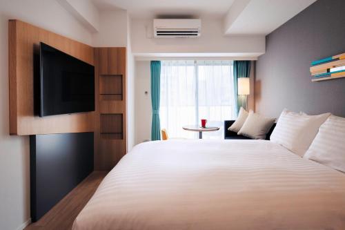 东京Oakwood Apartments Nishi-Shinjuku的酒店客房设有一张大床和一台电视。