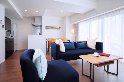 东京Oakwood Apartments Nishi-Shinjuku的客厅配有蓝色的沙发和桌子