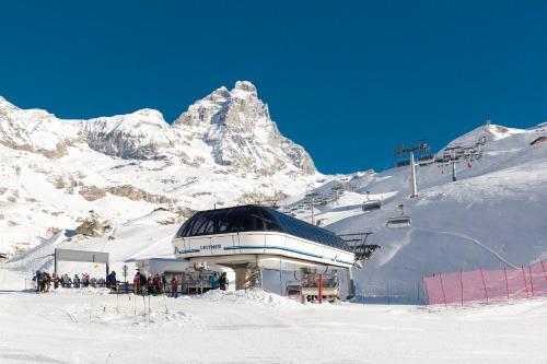 布勒伊-切尔维尼亚HelloChalet - Maison Rêve Blanc - Ski to door with Matterhorn view的一座白雪覆盖的山顶上的建筑