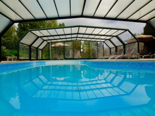 康卡勒Hotel Nuit Et Jour - La Maison de Lucile的一个带玻璃屋顶和椅子的游泳池