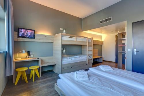 柏林梅尼奈格尔酒店柏林机场店的一间卧室配有两张床、一张桌子和两张凳子。