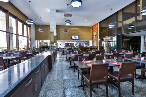 戈亚尼亚SJ Premium Hotels By Atlantica的一间带桌椅的餐厅和一间酒吧