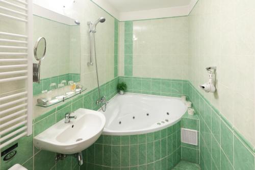 利贝雷茨Pytloun Self Check-in Hotel Liberec的绿色瓷砖浴室设有浴缸和水槽