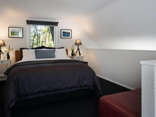 戴尔斯福特Gumnut Cottage Daylesford的一间卧室设有一张大床和一个窗户。