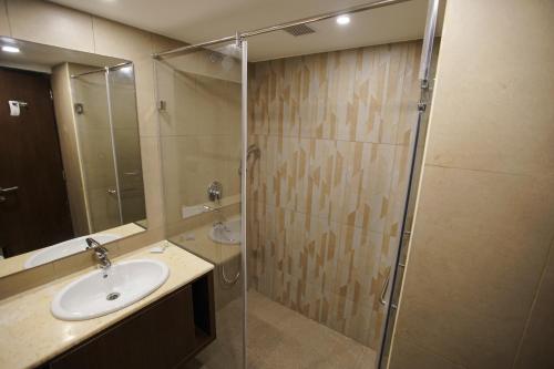 钦奈Jaag Hotel的一间带水槽和玻璃淋浴的浴室