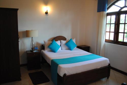 尼甘布苏耶瓦尼别墅的一间卧室配有一张带蓝色和白色枕头的床