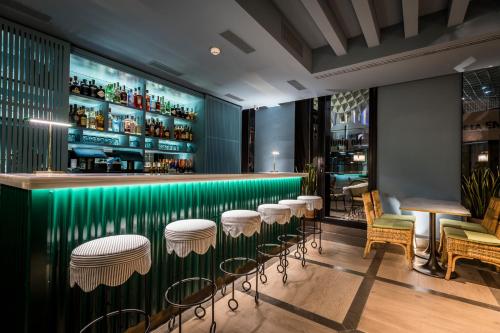 塞维利亚Intelier Casa de Indias的绿色酒吧设有凳子和桌椅