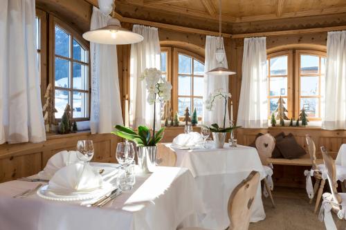 卡斯特尔罗托迈尔酒店的一间设有白色桌椅和窗户的用餐室