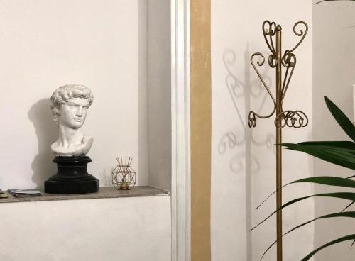 巴勒莫Qasr Home Beautiful apartment in Palermo的雕像坐在植物旁边的架子上