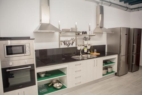 赫雷斯-德拉弗龙特拉Vivian's Guest House的厨房配有白色橱柜和不锈钢用具