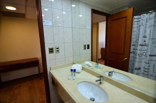 圣地亚哥Tur Hotel Santiago的一间带两个盥洗盆和大镜子的浴室