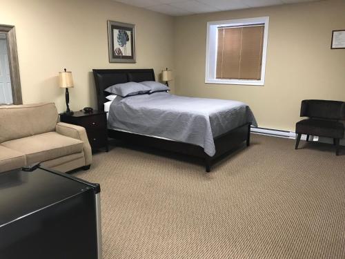 克拉伦维尔Riverview Suites的一间卧室配有一张床、一张沙发和一把椅子