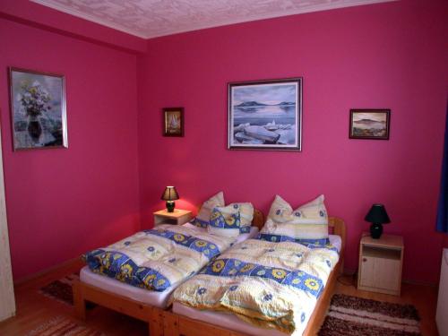 福纽德Apartment Fonyod 25的卧室拥有粉红色的墙壁,配有带枕头的床铺