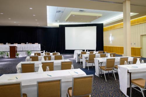 新卡罗尔顿华盛顿北梅特罗珀恩茨酒店的一间会议室,配有白色的桌椅和屏幕