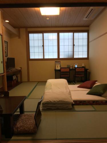 京都萨瓦亚宏腾日式旅馆的客房设有两张床、一张桌子和窗户。