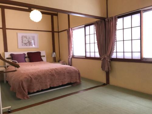 汤泽町Naeba Ski Resort & Fuji Rock的一间卧室设有一张床和两个窗户。