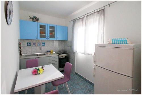 普利莫顿Apartments Zoro的厨房配有蓝色橱柜、桌子和冰箱。