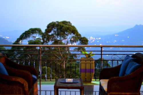 姆巴巴内Rehoboth Mountain Suites的阳台配有2把椅子和1张桌子,享有风景。