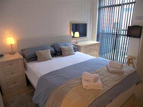 曼彻斯特Stay Deansgate Apartments for 14 nights plus的一间卧室配有一张大床和两条毛巾