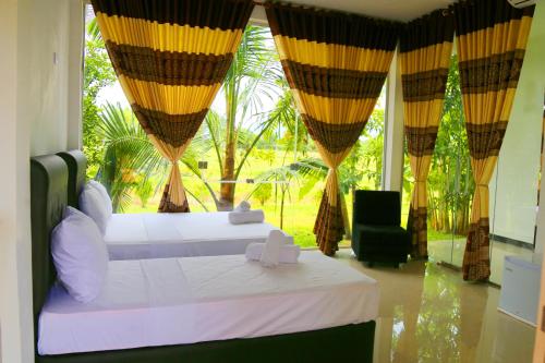 波隆纳鲁沃Rivonway Hotel Polonnaruwa的一间卧室设有两张床和大窗户
