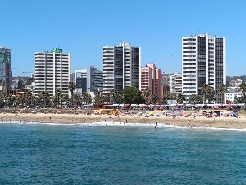 维纳德马Departamento Reñaca maravillosa vista al mar的一群人住在水里和建筑物中的海滩