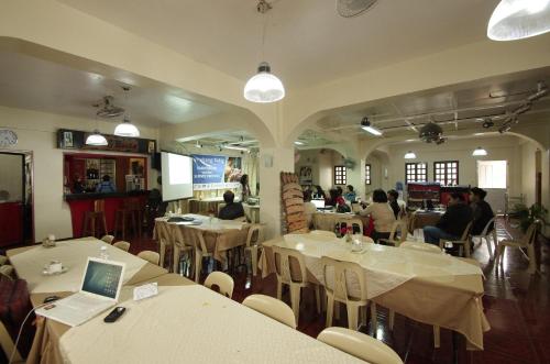 巴斯科Batanes Seaside Lodge & Restaurant的一间设有白色桌子的餐厅,有坐在桌子上的人